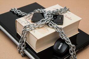 Picture of a computer and books surounded by chains.