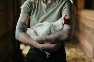 Homesteading woman holding a rooster conducting a workshop.