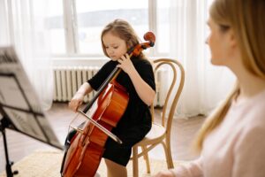 Woman working with student to teach the cello.