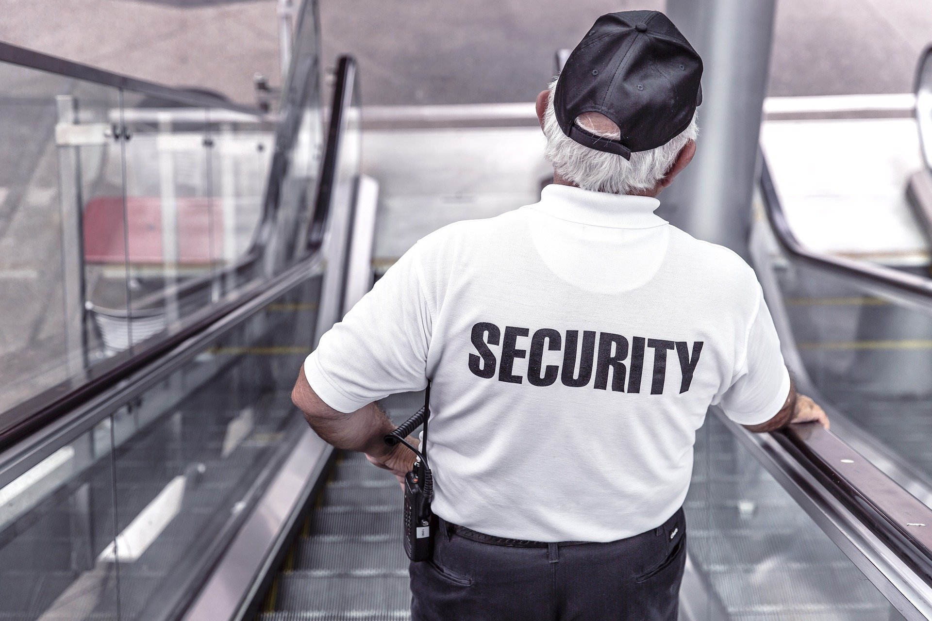 Security guard going down an escalator in a building.