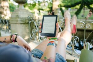 Woman reading an ebook written by someone learning how to make money on 10 acres of land.