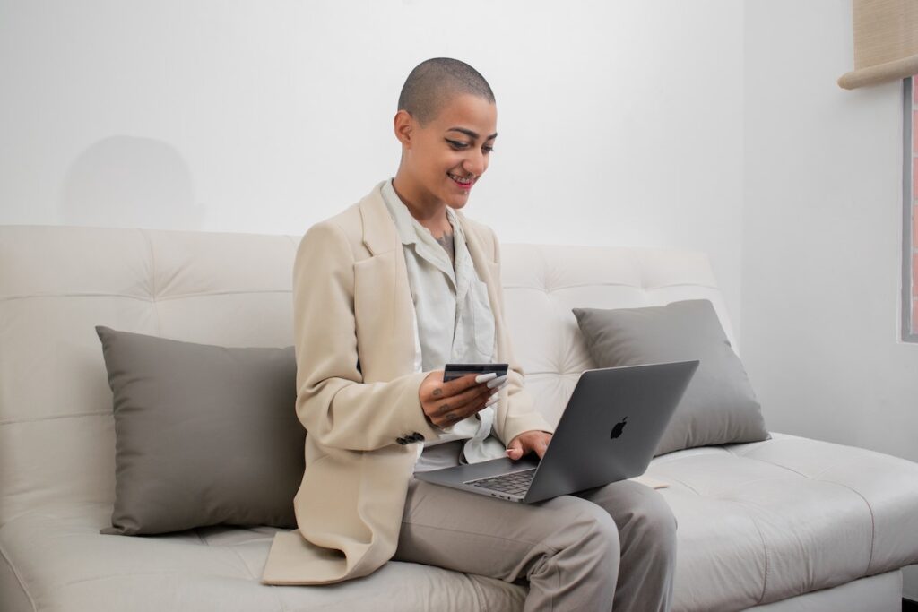 Woman holding a bank card sitting at her laptop