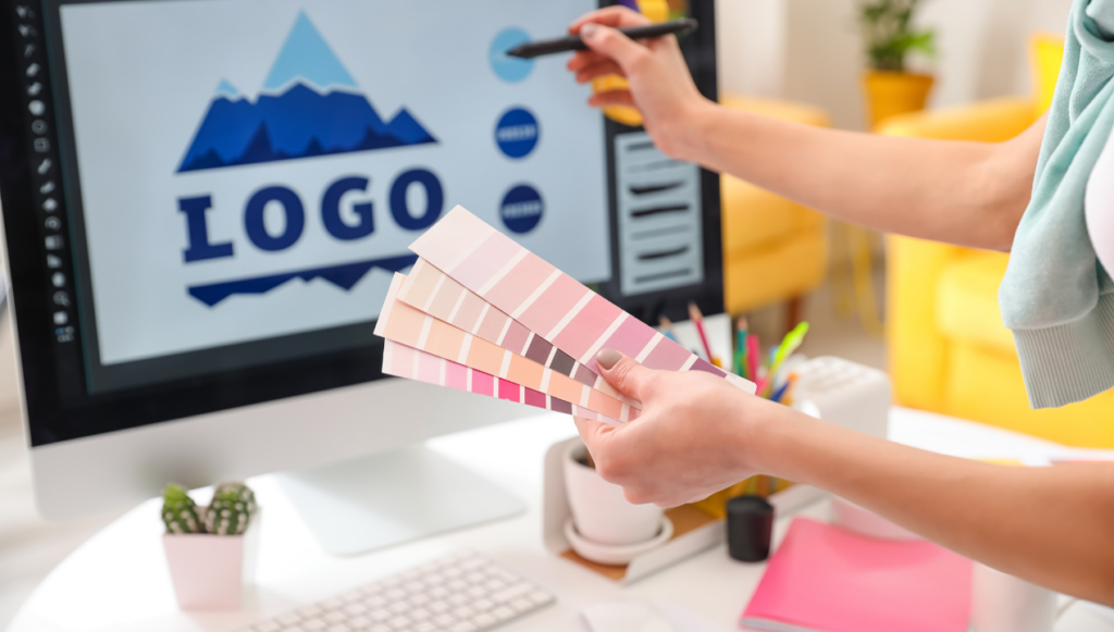 Online Weekend Job - a designer with a handful of colour cards pointing at a monitor with a logo design 