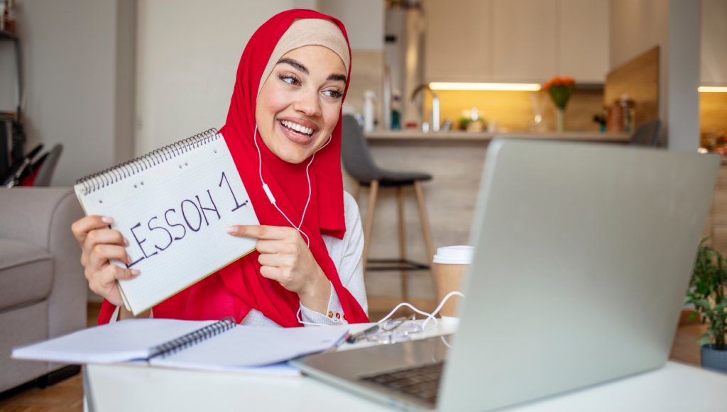 work from home jobs no experience,
an online tutor working from home holding up a pad with the words Lesson 1 written on it in front of a laptop