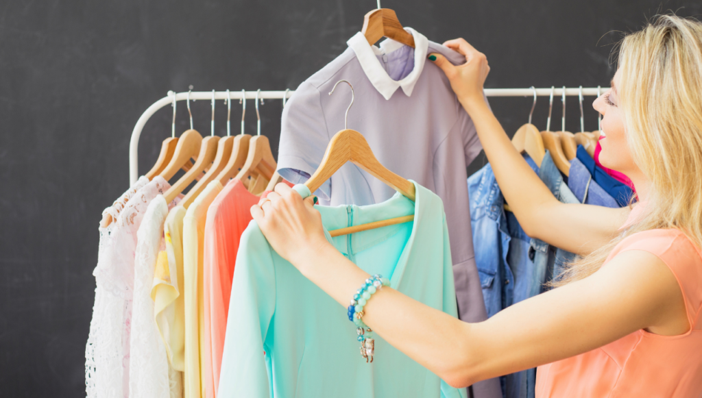 creative business ideas - a woman standing by a clothes rail holding up two different garments to compare them