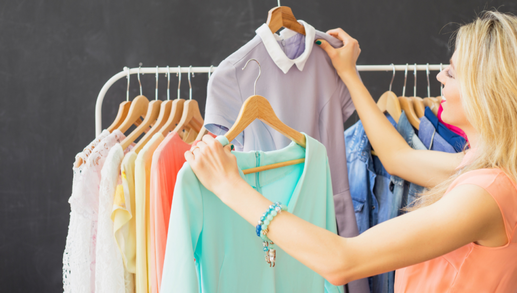 creative business ideas - a woman standing by a clothes rail holding up two different garments to compare them 