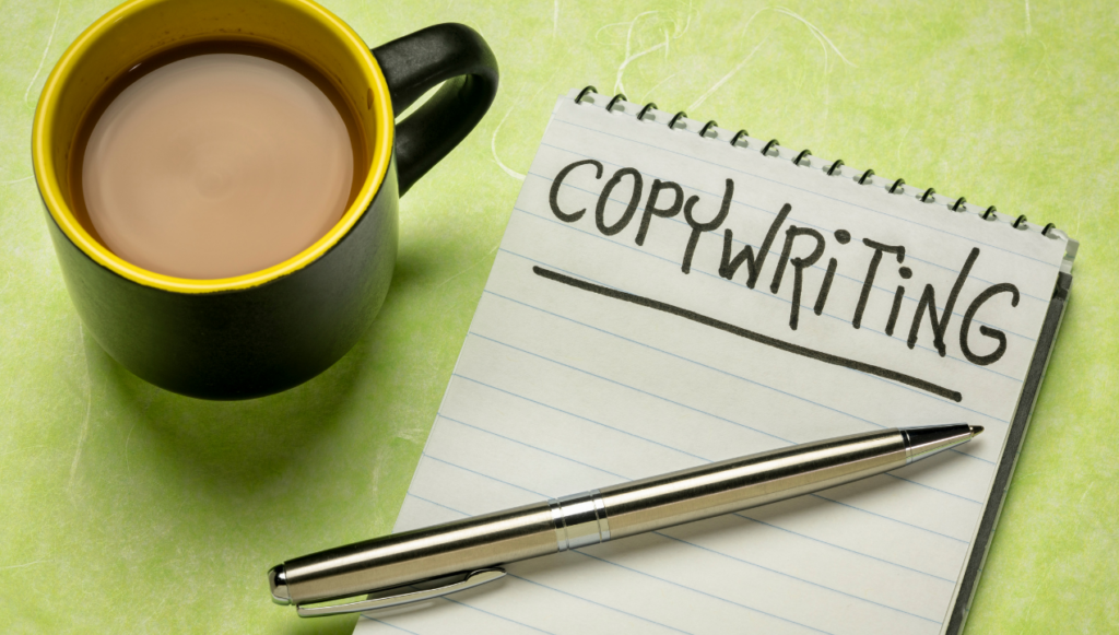 Remote freelance writing jobs for beginners - a jotter pad with the word copywriting written on it and a mug of tea alongside