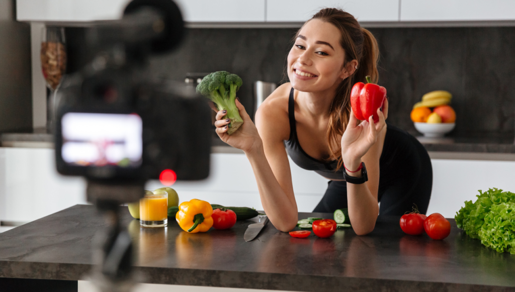 creative business ideas - a foodie youtuber holding up different vegetables in front of the camera and smiling