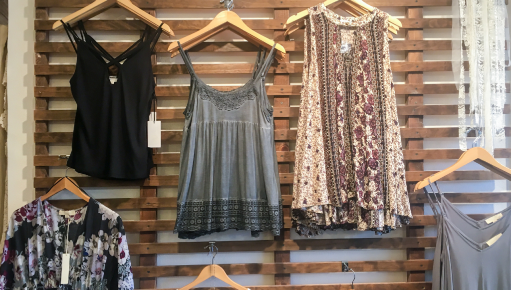 Clothing Business Name Ideas - a display of boho type clothes against a wooden rack on a wall