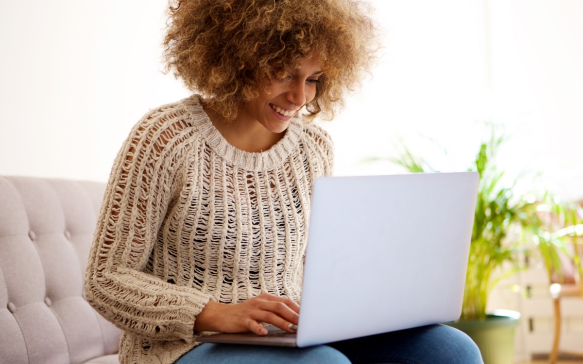 a young woman smiling and typing on her laptop