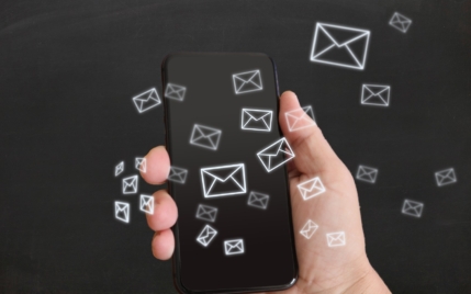 email icons floating over a cell phone in a person