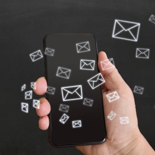 email icons floating over a cell phone in a person's hand