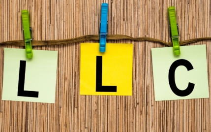 the letter L, L, and C written on square pieces of paper and clipped to a string for the best llc service.